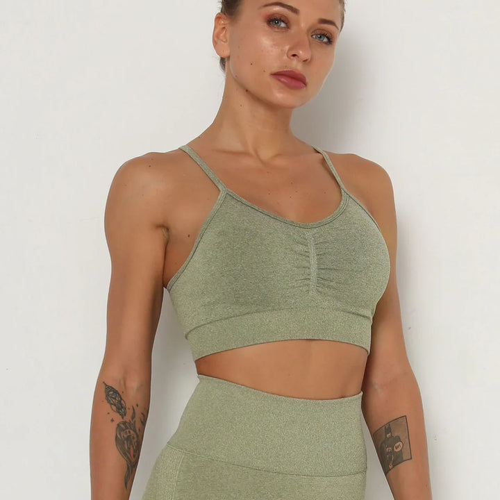 fit woman wearing green seamless sports bra and high-waisted leggings with arm tattoos
