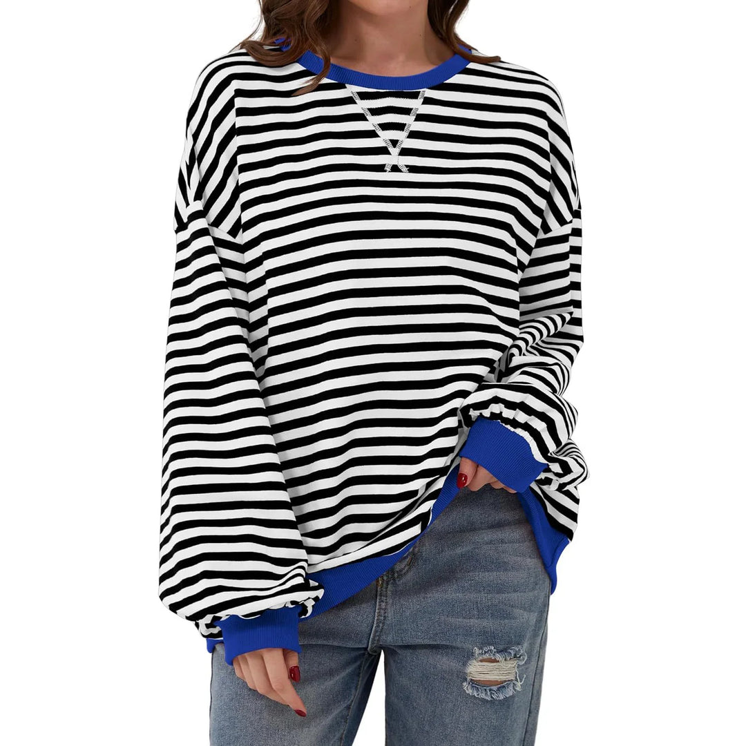 Woman wearing black and white striped sweatshirt with blue cuffs and collar, paired with ripped jeans