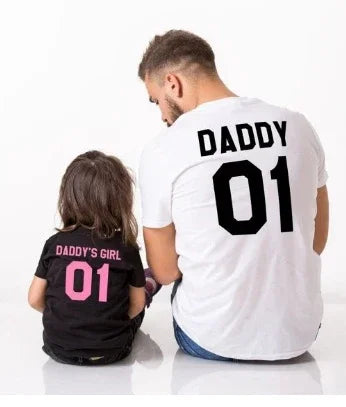 Father and daughter wearing matching shirts with Daddy 01 and Daddy's Girl 01 printed on back