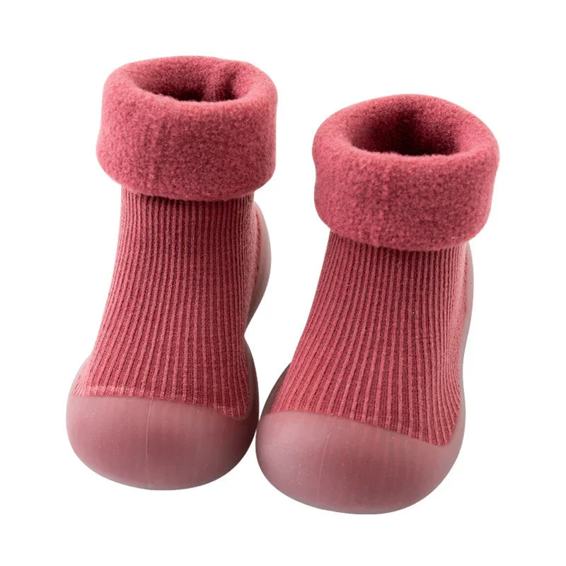 Pink toddler socks with flexible rubber soles and cozy fleece cuffs on white background