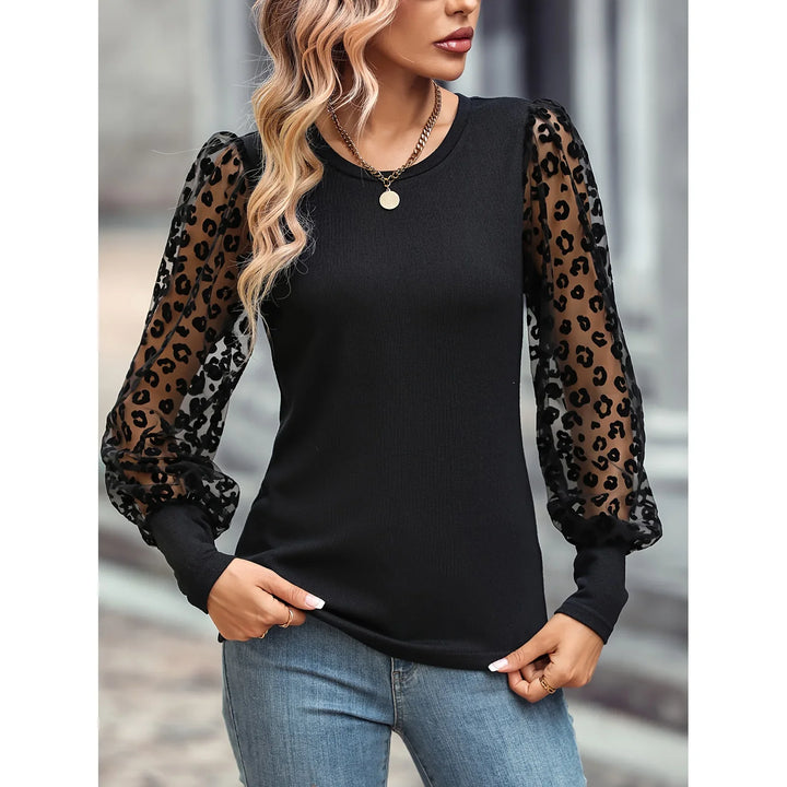Woman wearing black top with sheer leopard print puff sleeves paired with blue jeans