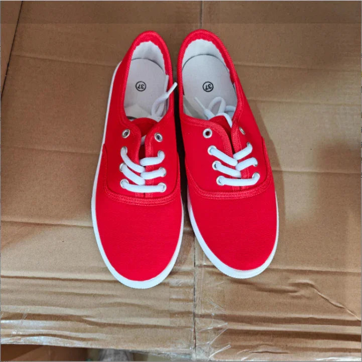 Pair of red canvas sneakers with white laces and soles on a cardboard surface, size 37