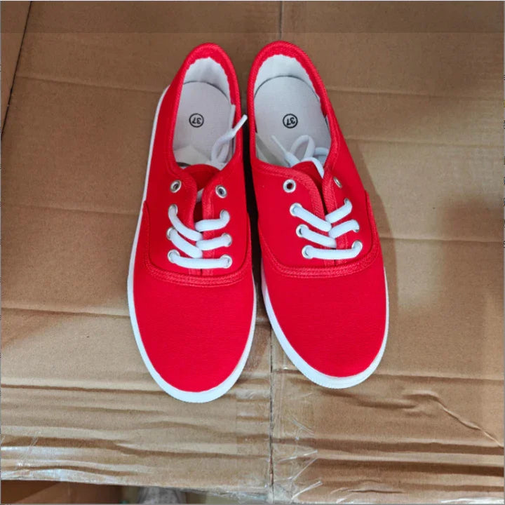 Pair of red canvas sneakers with white laces and soles on a cardboard surface, size 37
