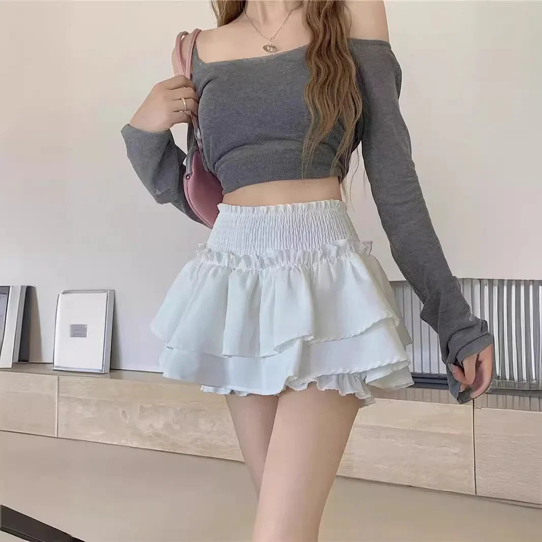 Woman wearing gray off-shoulder crop top and white layered ruffle mini skirt indoors