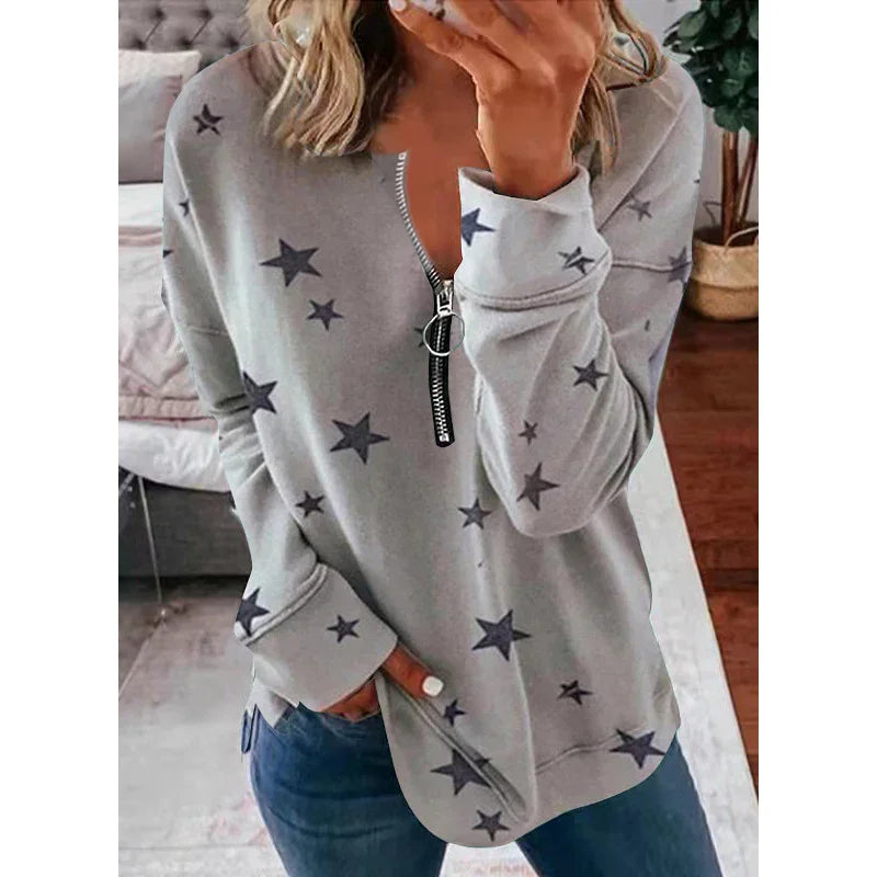 Woman wearing grey star print zipper pullover sweatshirt with blue jeans indoors