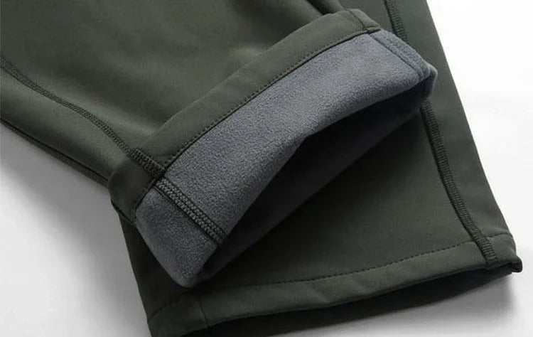 Close-up of dark green fleece-lined pants cuff with detailed stitching on white background