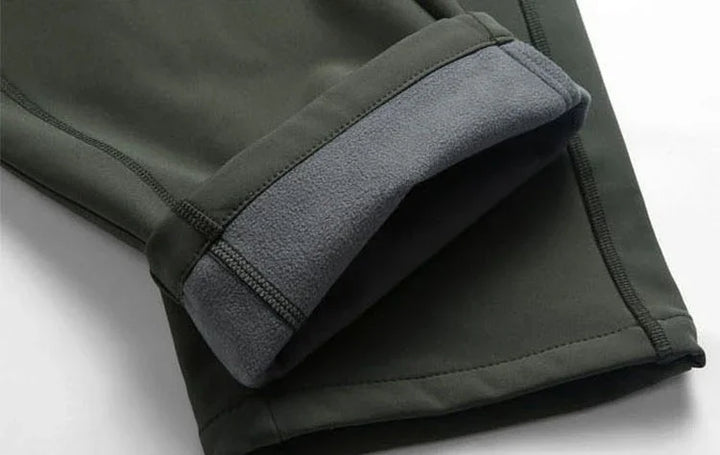 Close-up of dark green fleece-lined pants cuff with detailed stitching on white background