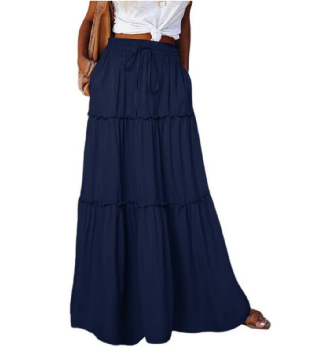 Woman wearing navy blue tiered maxi skirt with drawstring waist and pockets, paired with white knotted top