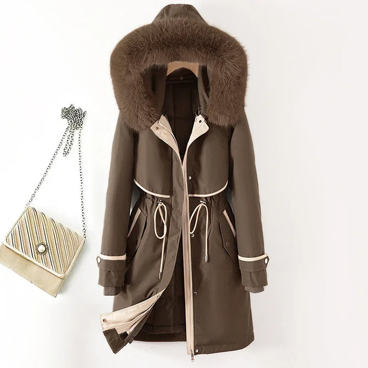 brown winter parka with fur hood, drawstring waist, and beige trim hanging next to striped chain purse
