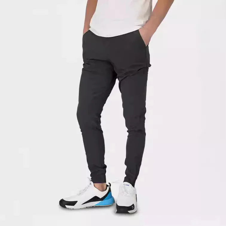 Man wearing black slim-fit jogger pants and white athletic sneakers with blue accents