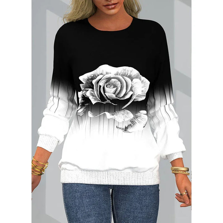 Woman wearing black and white ombre sweatshirt with large detailed rose print and ribbed cuffs