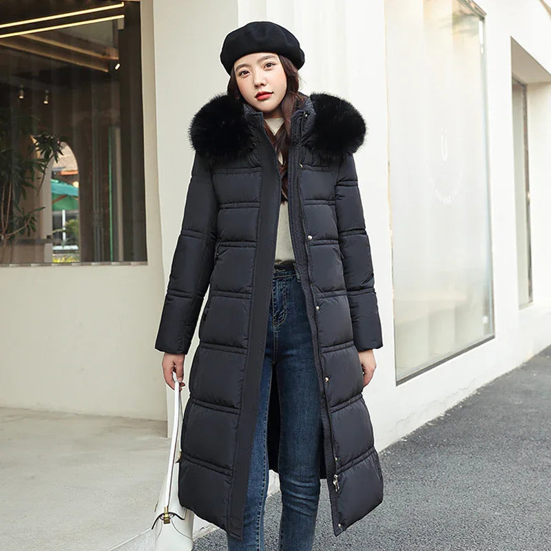 Woman wearing long black puffer coat with fur collar and black beret, holding white handbag outdoors