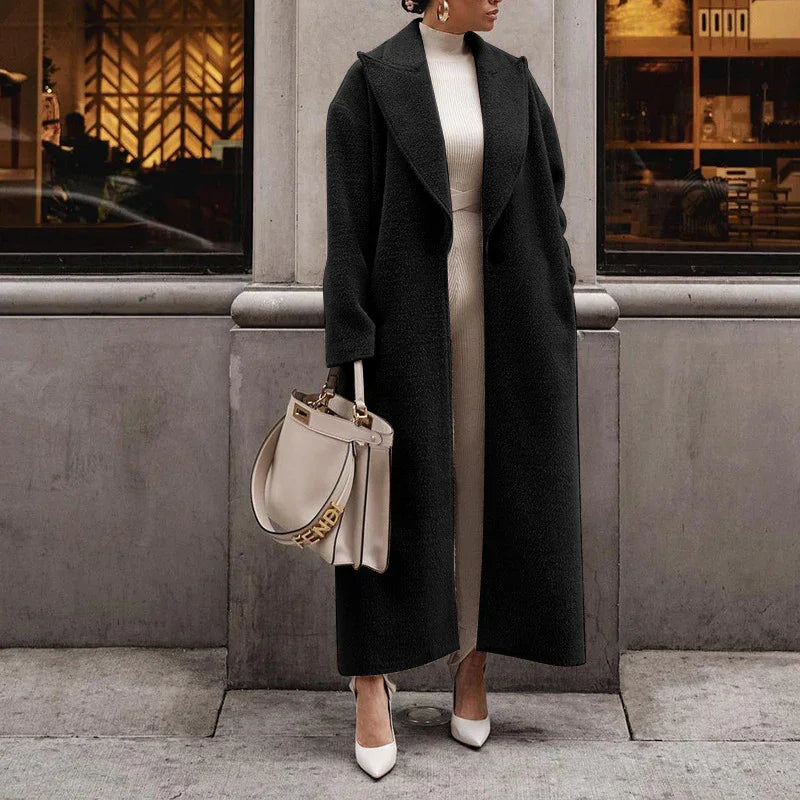 Woman wearing long black coat, white dress, white heels, carrying beige Fendi handbag outdoors