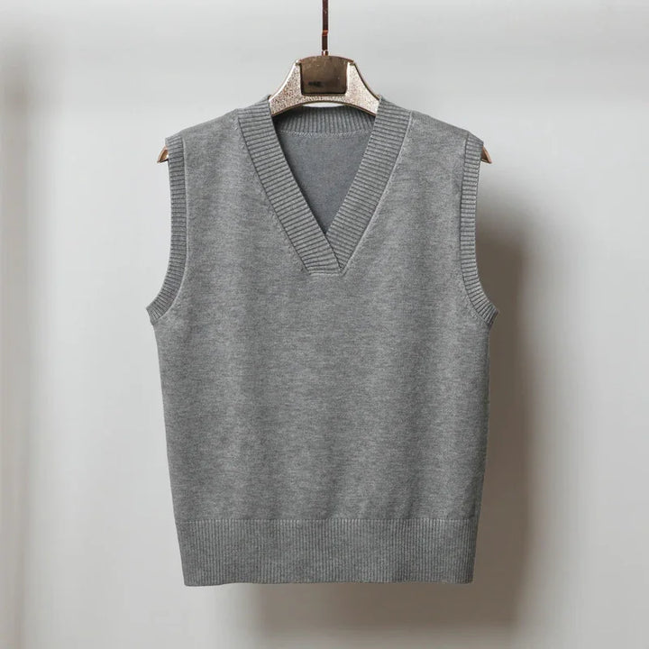 Gray sleeveless V-neck knit sweater vest hanging on wooden hanger against white background