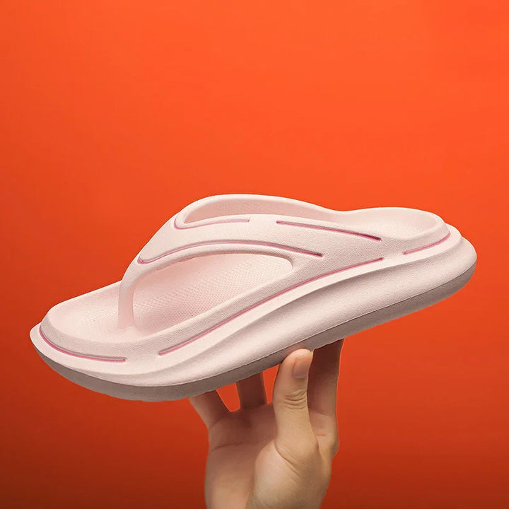 Hand holding a pink cushioned flip flop sandal with orange background