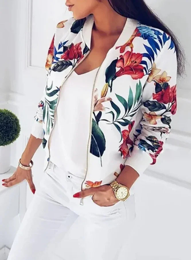 Woman wearing white floral print bomber jacket with red and blue flowers, paired with white top and pants