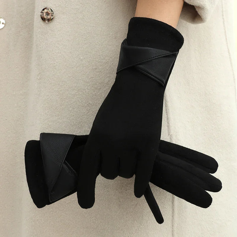 Pair of black winter gloves with leather trim held against beige coat background