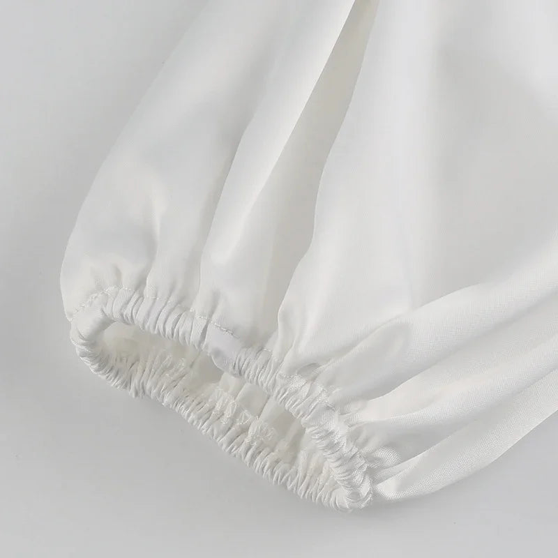 Close-up of white fabric sleeve with elastic cuff detail on plain background