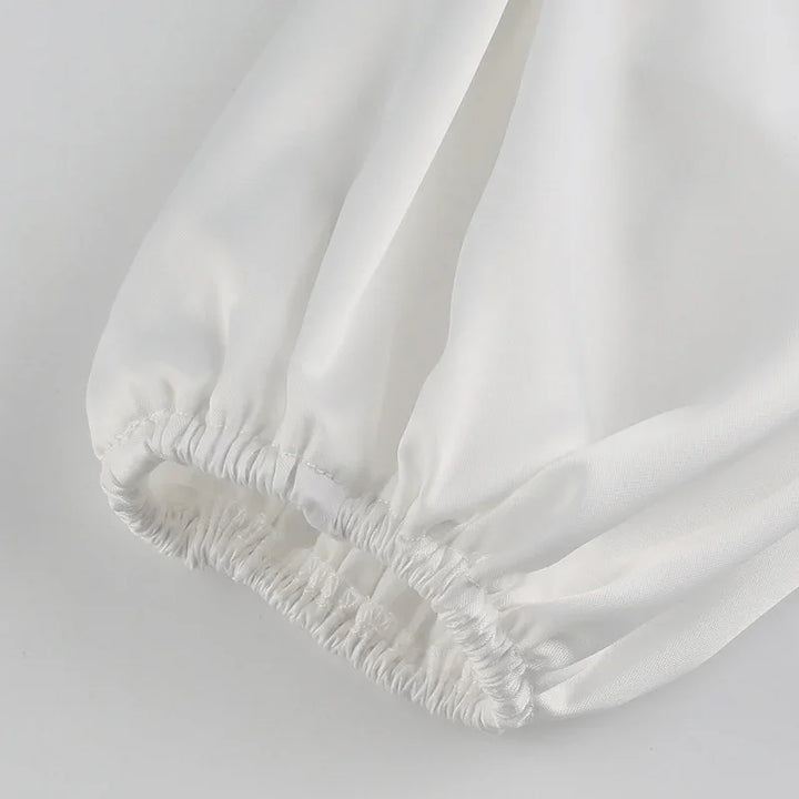 Close-up of white fabric sleeve with elastic cuff detail on plain background