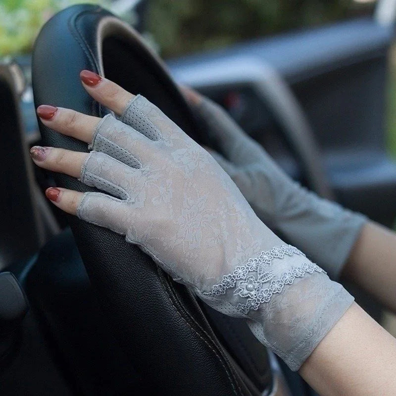 hands wearing elegant gray floral lace fingerless gloves on a black car steering wheel