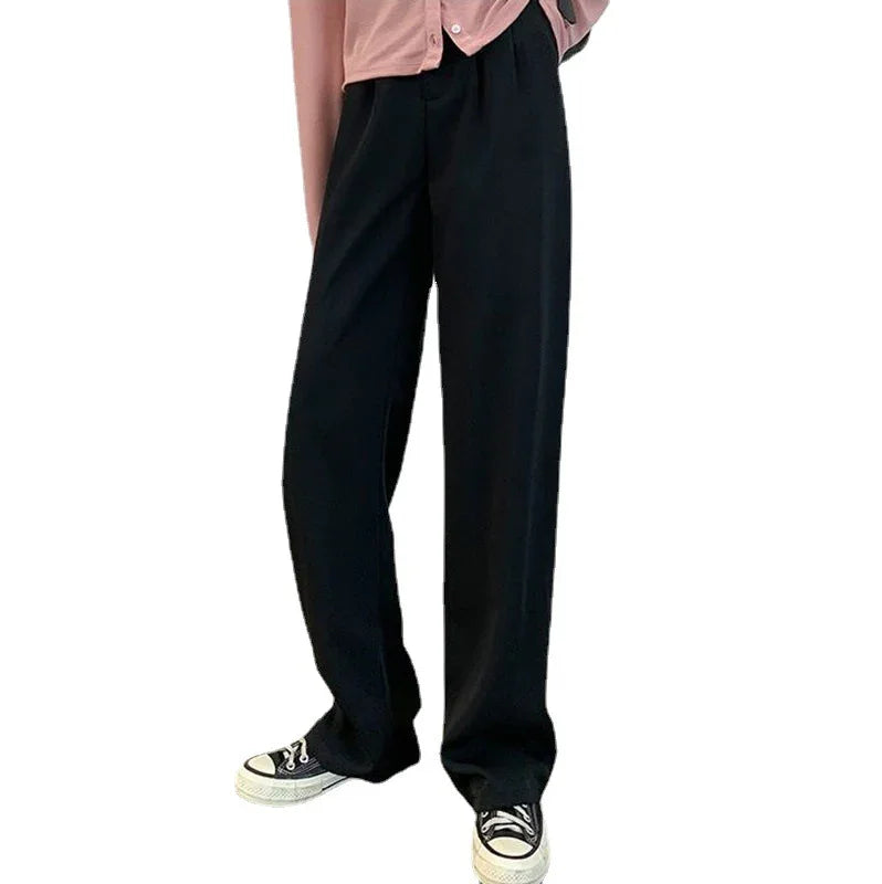 Person wearing loose black pants paired with black and white sneakers and a pink top