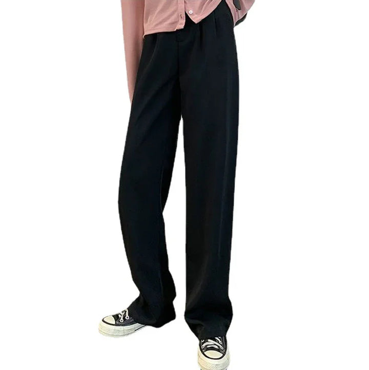 Person wearing loose black pants paired with black and white sneakers and a pink top