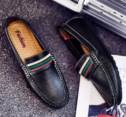 Black leather men's loafers with green and red striped accent on textured gray surface