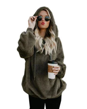 woman wearing oversized fuzzy olive green hoodie with hood up, holding coffee cup and wearing round sunglasses