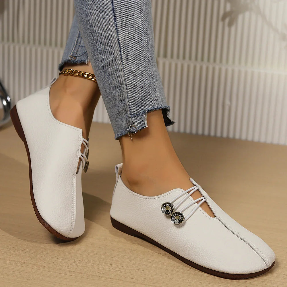 White casual flat shoes with decorative buttons worn with frayed hem blue jeans and gold anklet