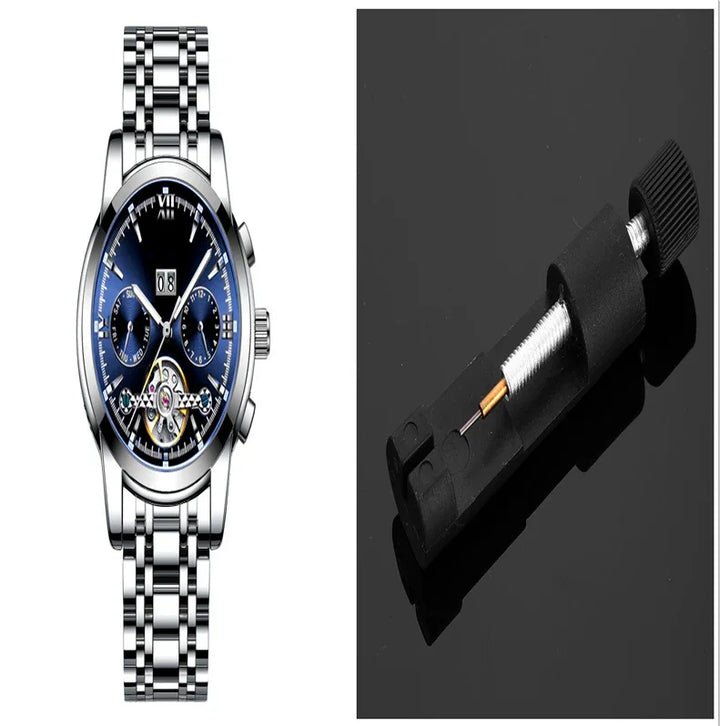 Silver stainless steel wristwatch with blue dial and dual subdials beside black watch spring bar tool on black surface