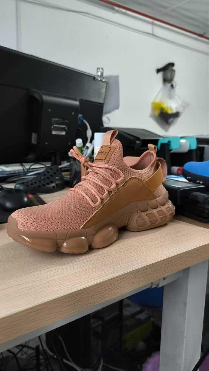 Brown sporty sneaker with textured sole on wooden office desk with computer and accessories