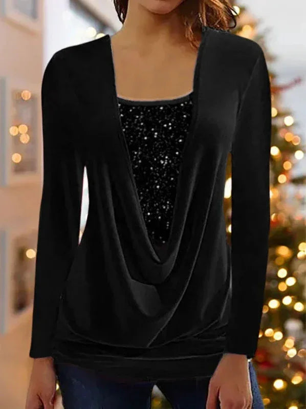Woman wearing black long-sleeve top with deep draped neckline and sparkly inner layer, holiday lights background