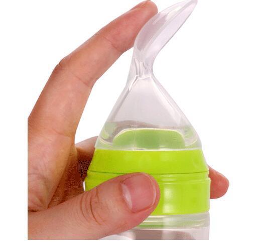 Hand holding a green and clear nasal aspirator with a curved tip for baby care