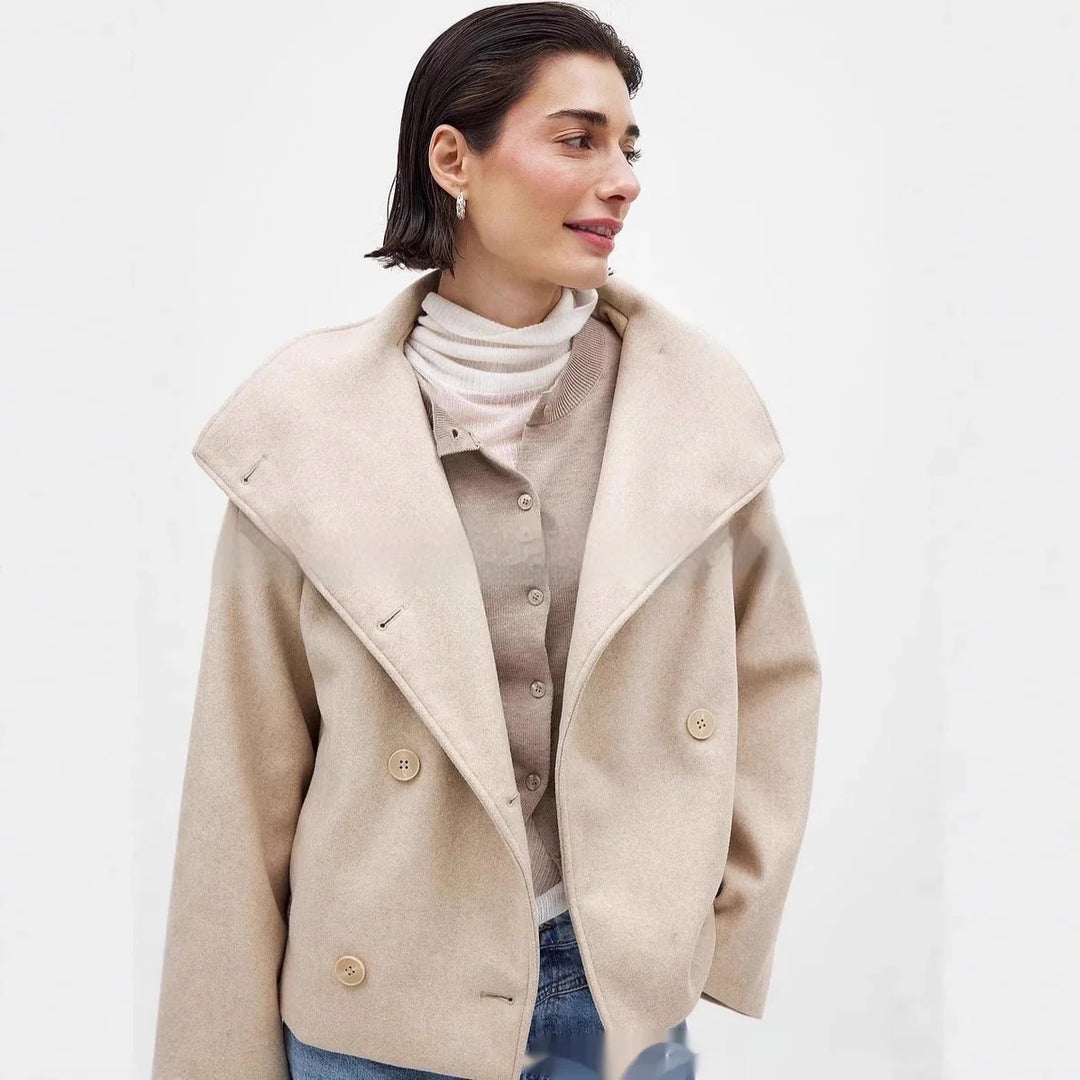 Woman wearing beige wool double-breasted coat, layered with cardigan and striped turtleneck