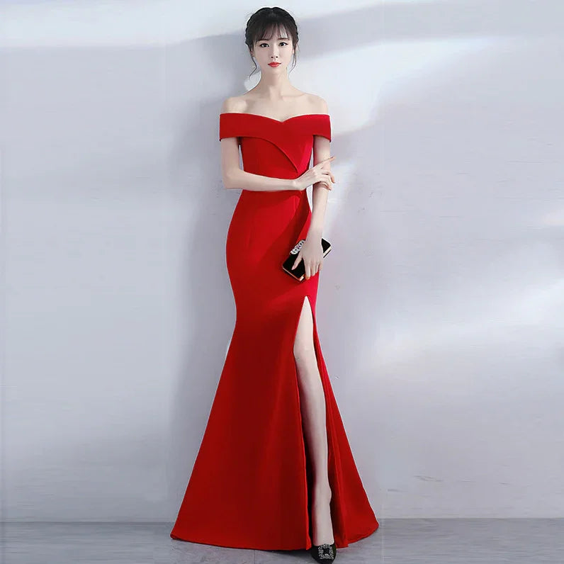 Elegant woman in a red off-shoulder evening gown with thigh-high slit holding a black clutch
