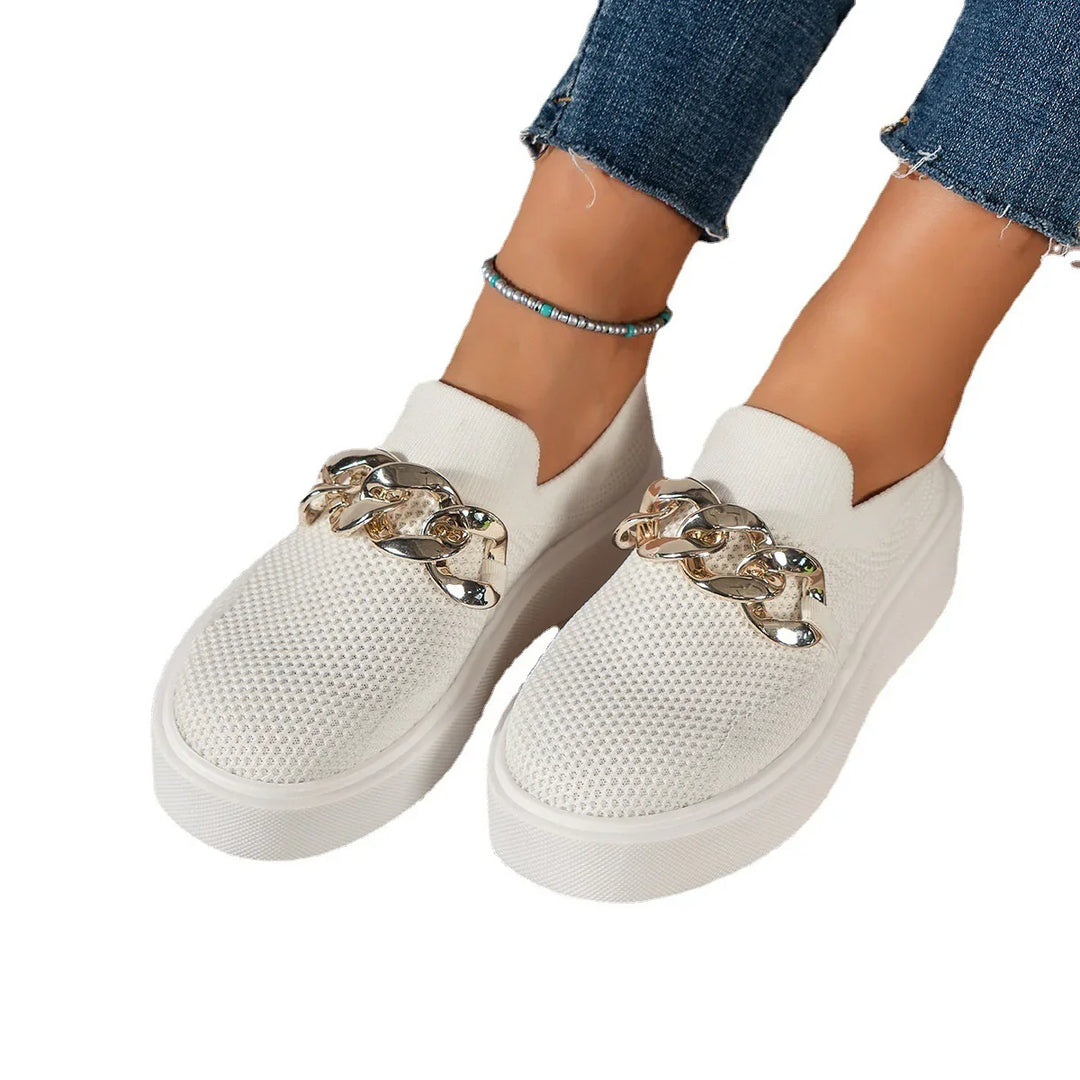 White textured slip-on sneakers with large gold chain detail worn with cropped blue jeans and beaded anklet
