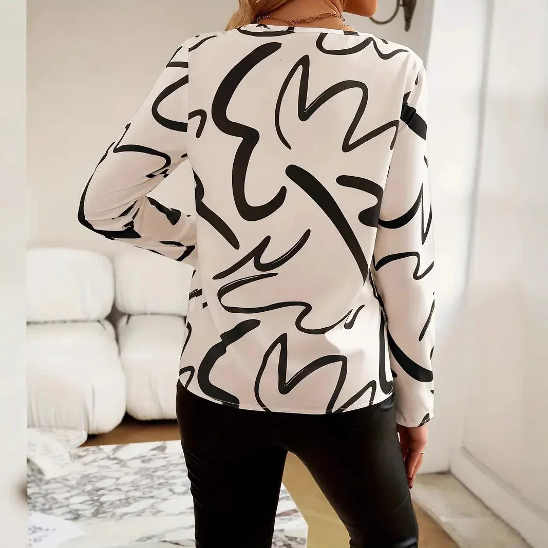 Woman wearing white blouse with black abstract print and black pants in modern white living room