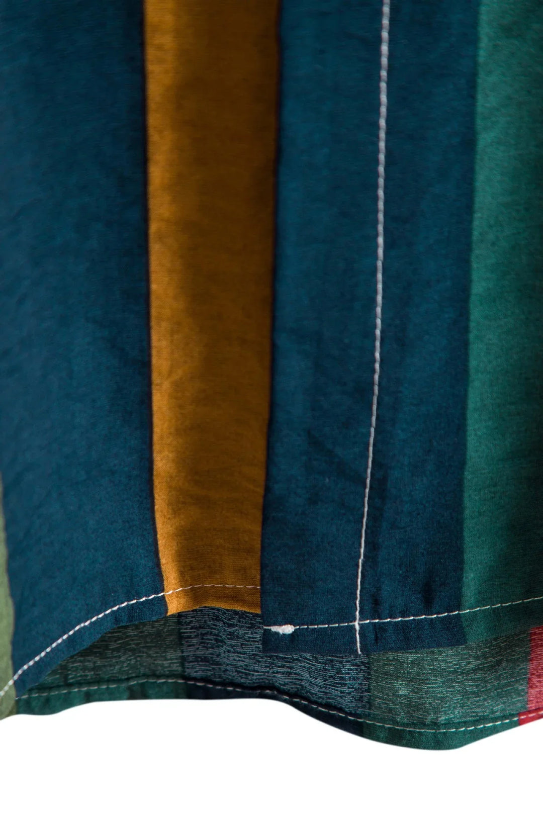 Close-up of multicolor striped fabric with blue, green, mustard, and red vertical stripes and white stitching