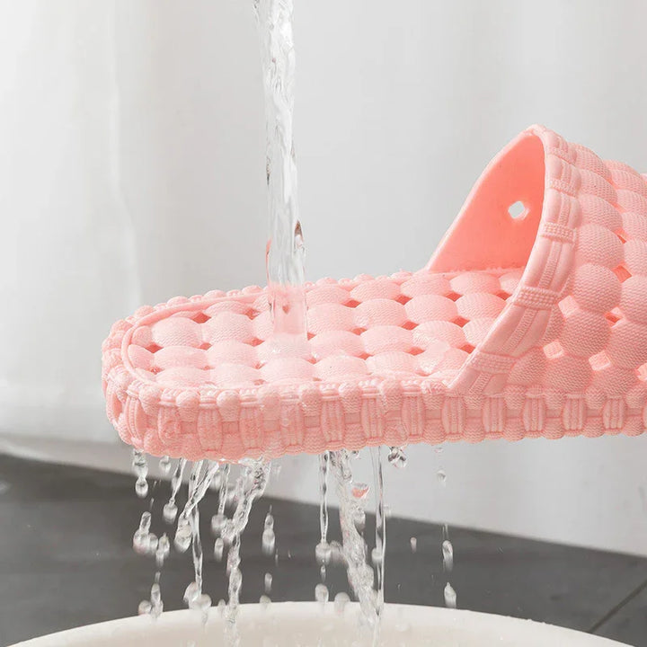 Pink textured shower sandal with water flowing through for quick drainage and drying