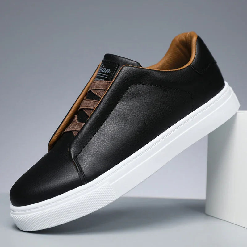Black leather sneaker with brown inner lining and laces, white rubber sole on gray background