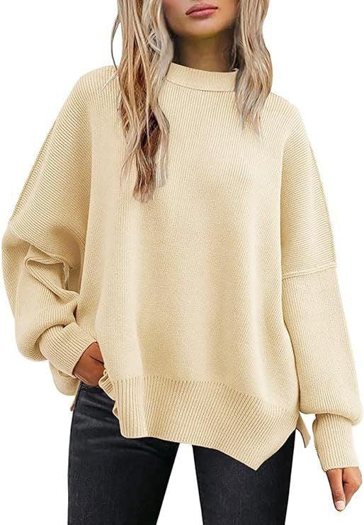 Woman wearing oversized beige knit sweater with ribbed cuffs and hem, paired with black pants