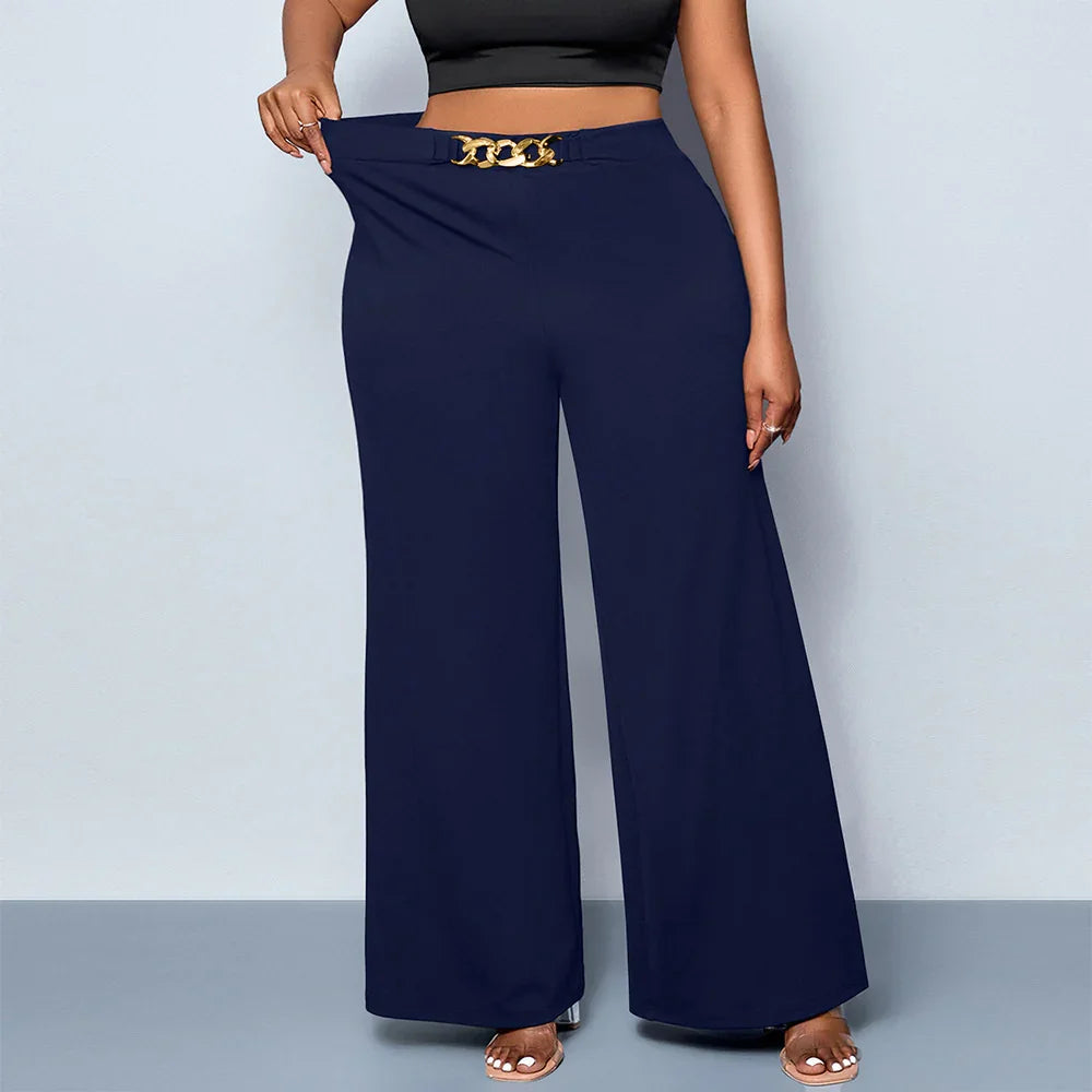 Plus size woman wearing navy wide-leg pants with gold chain belt detail and black crop top