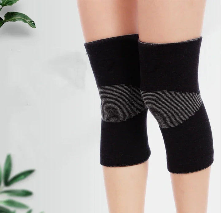 Black knee compression sleeves worn on legs, with a plant in the background