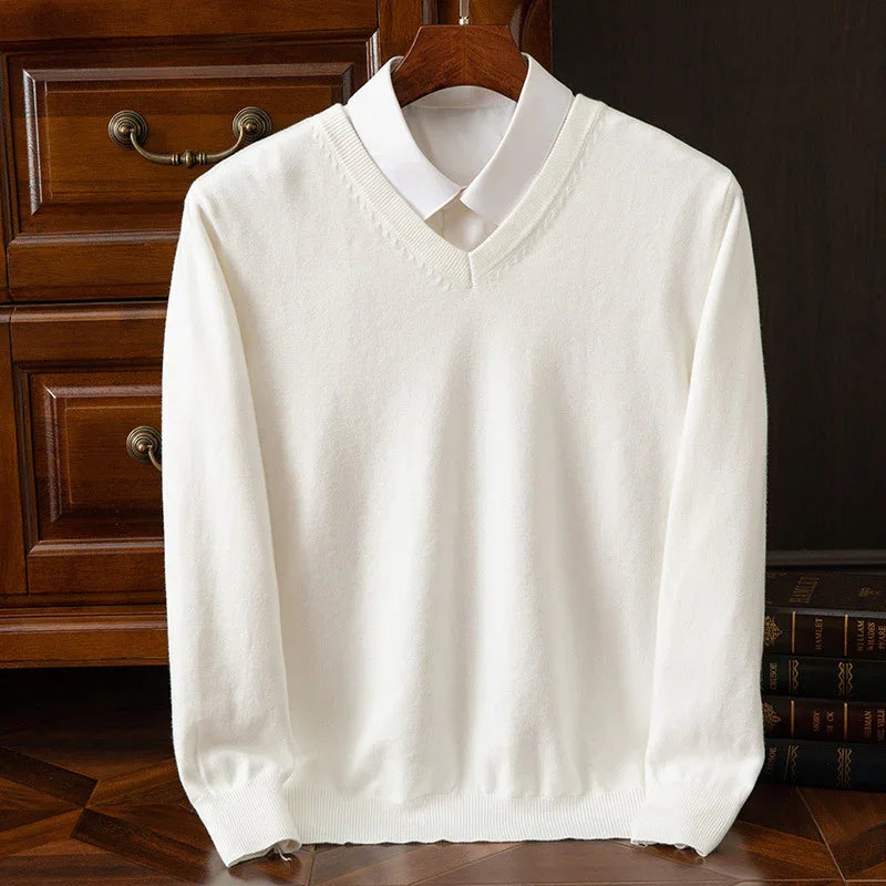 White V-neck sweater over a white shirt on a hanger against wooden drawers and stacked books