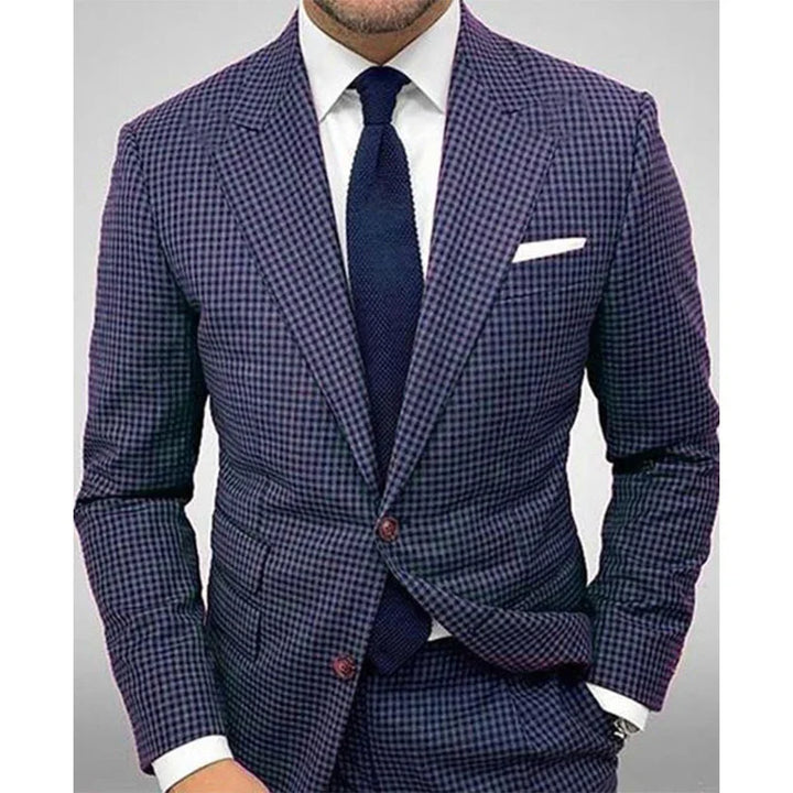 Man wearing navy blue checkered suit with white dress shirt, navy tie, and white pocket square