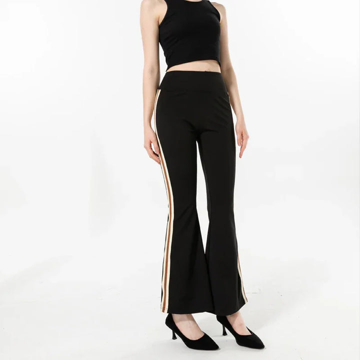 Woman wearing black flared pants with white and brown side stripes and black sleeveless crop top