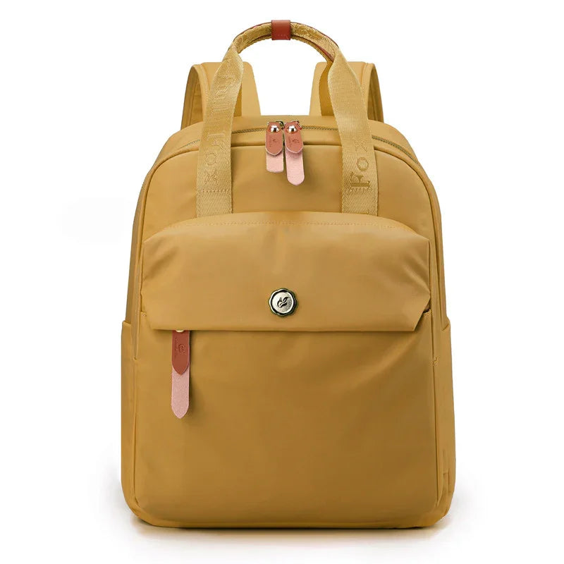 Mustard yellow backpack with front pocket, pink leather zipper pulls, and top handle straps