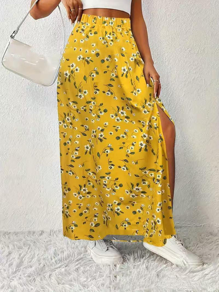 Woman wearing a yellow floral maxi skirt with a side slit, white crop top, white sneakers, and clear handbag