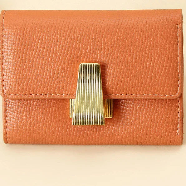 Close-up of a textured tan leather wallet with a shiny gold clasp on a light background
