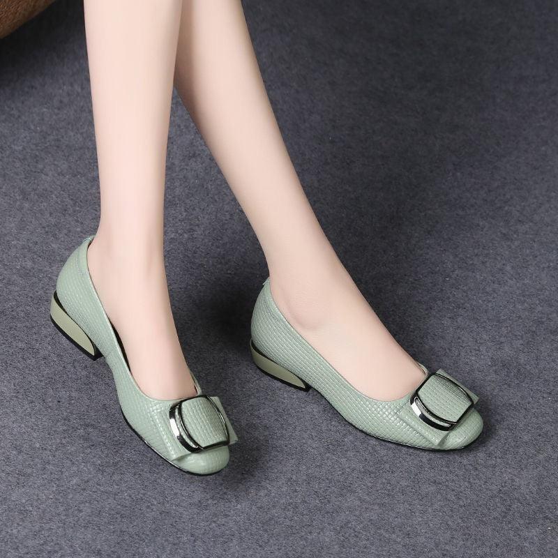 Women's light green textured low heel shoes with large buckle detail on grey carpet